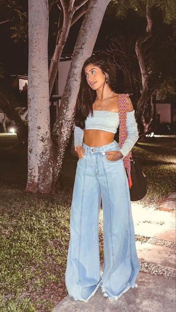 Moça usando look com calça pantalona jeans claro e cropped