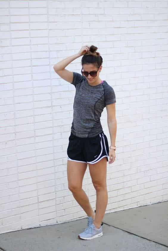 look de academia feminino com camiseta esportiva cinza e shorts larguinho