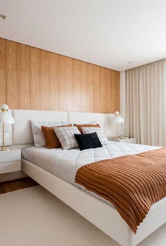 cama arrumada com peseira para quarto decorado em cores neutras com parede de madeira