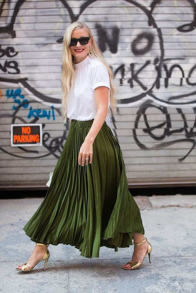 camiseta branca para look com saia plissada verde e sandalia dourada