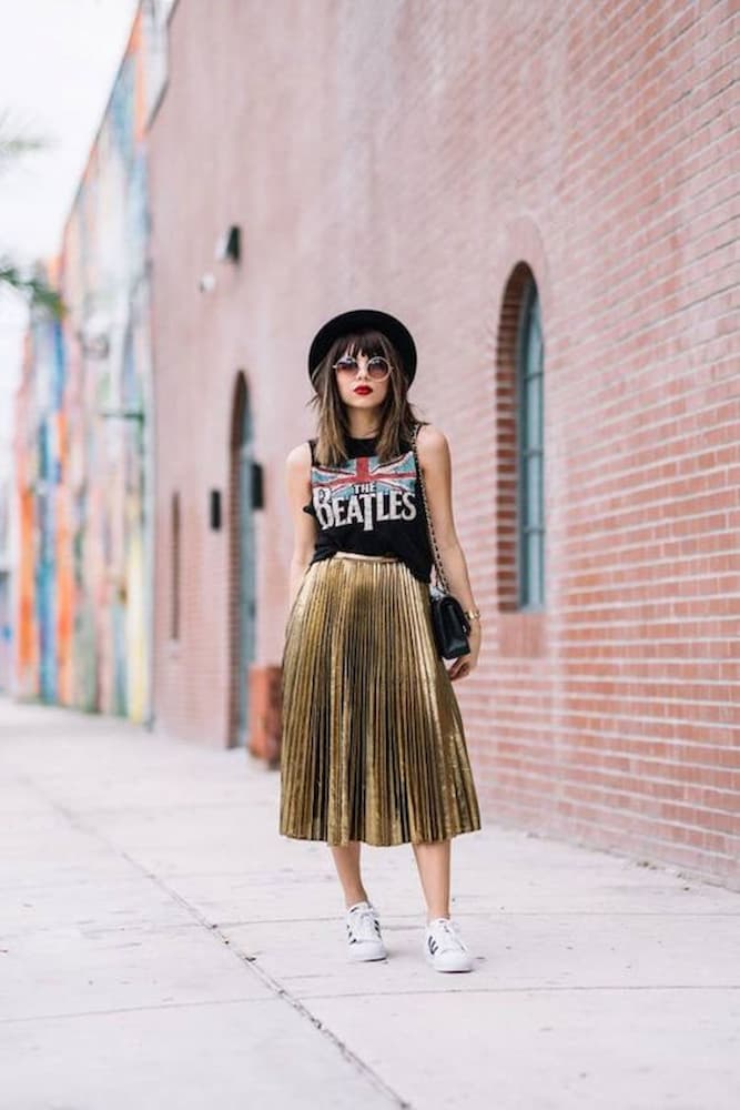 look dourado com saia midi plissada e camiseta de banda