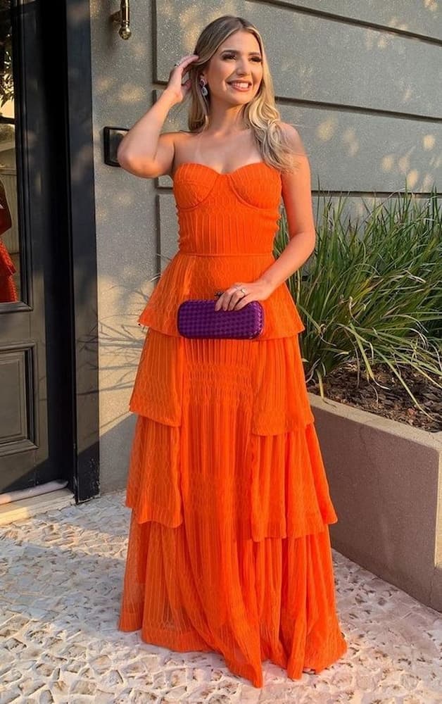 look para casamento de dia com vestido laranja e clutch roxa 