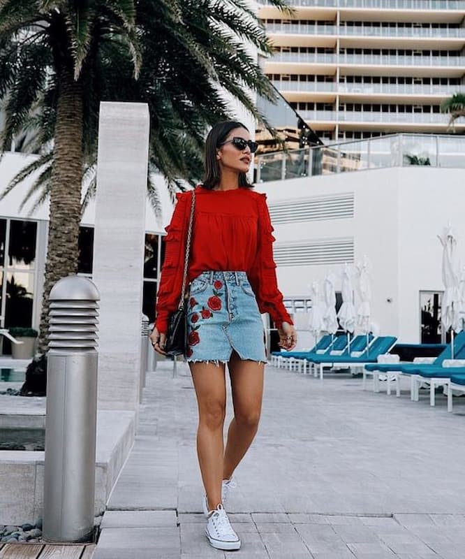 suéter vermelho para look com saia jeans curta e tênis 